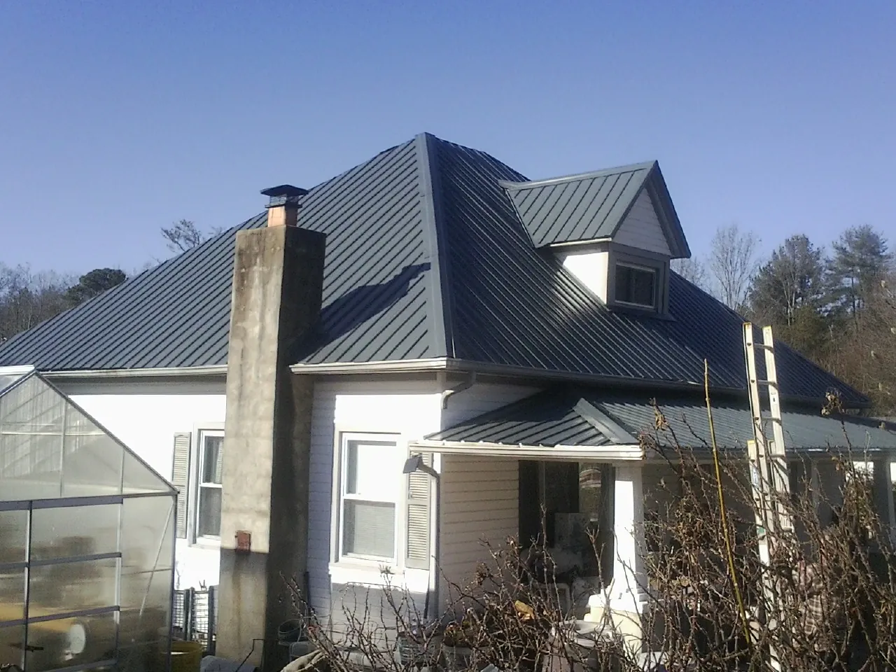 Dark blue standing seam metal roof on a white farmhouse with dormer — Slate & Tile Roof Repair by Roofing Brothers in Anoka