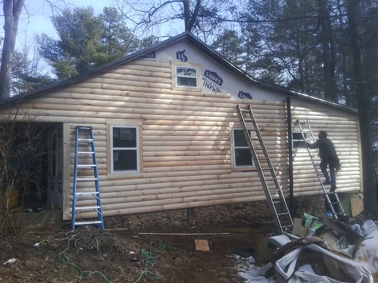 Ladders set against fresh log siding during an exterior remodel in Anoka