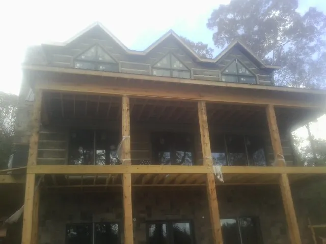 Dormers and porch framing on a large log home under construction — Roof Coating work by our crew in Anoka