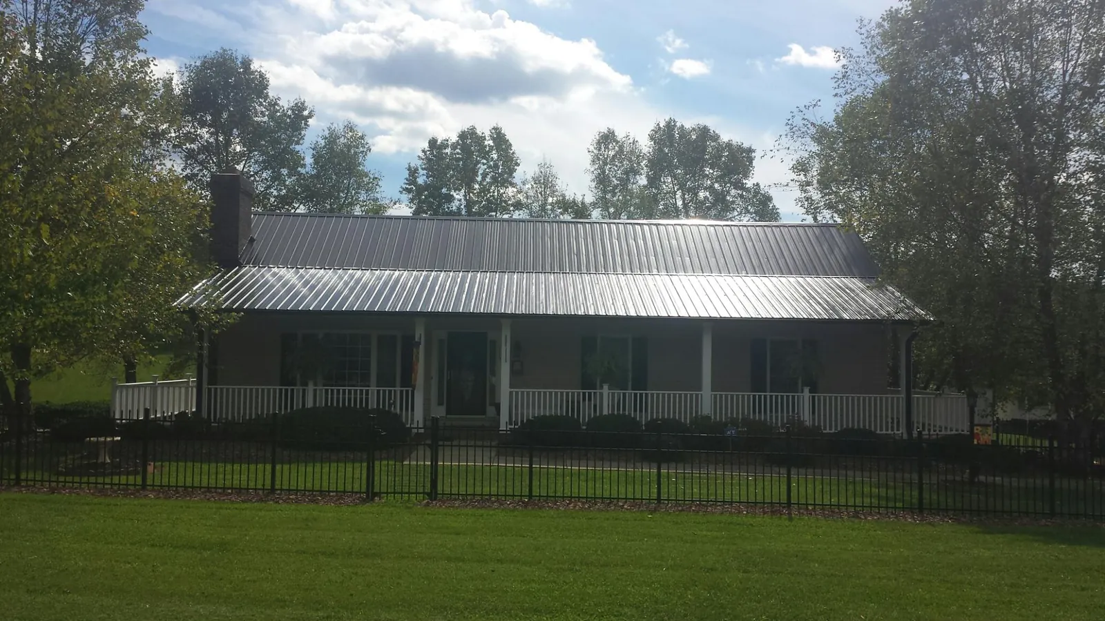 Gray metal roof on a brick ranch with a full width front porch — Gutter Guard Installation work by our crew in Anoka