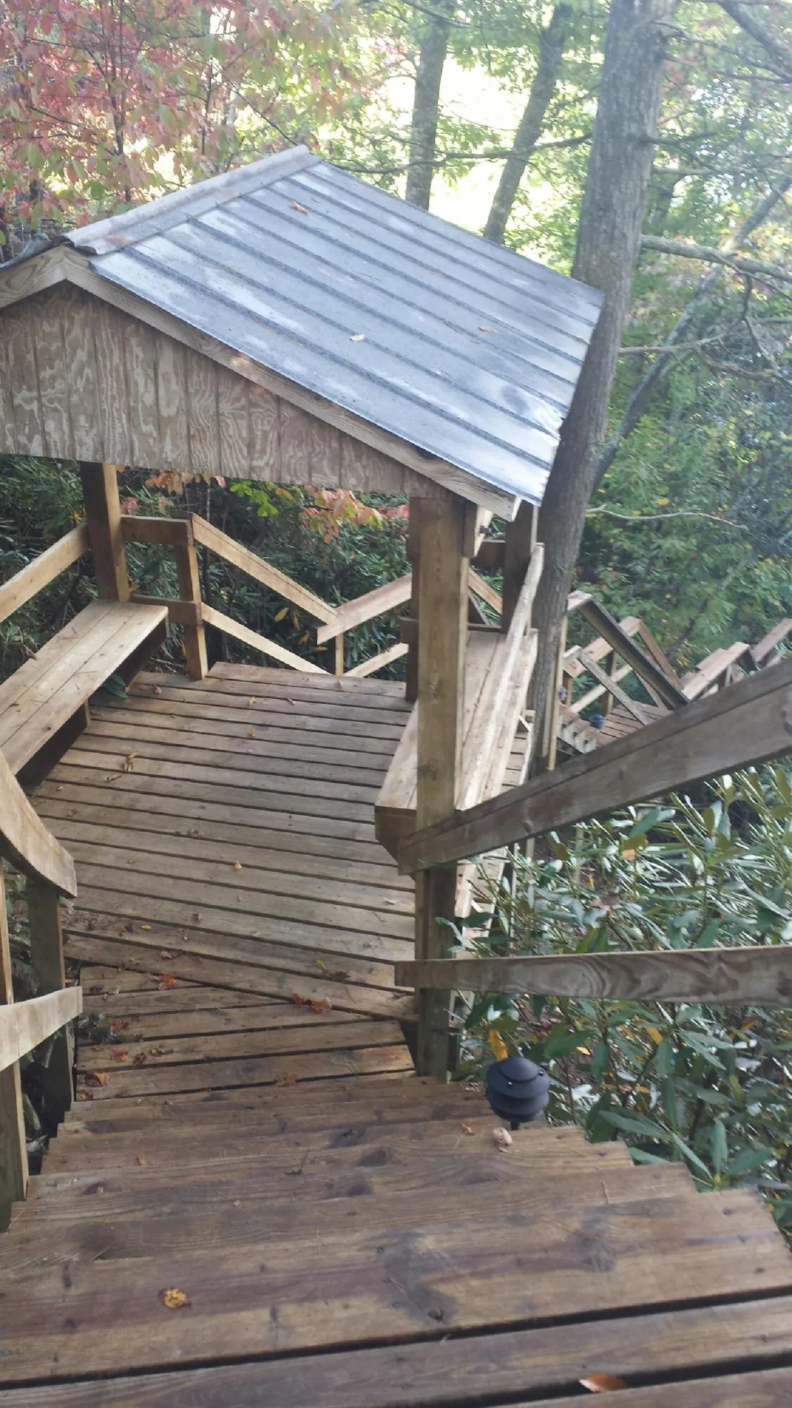 Metal roofed shelter over wooden steps on a wooded walkway — Skylight Repair & Installation work by our crew in Anoka