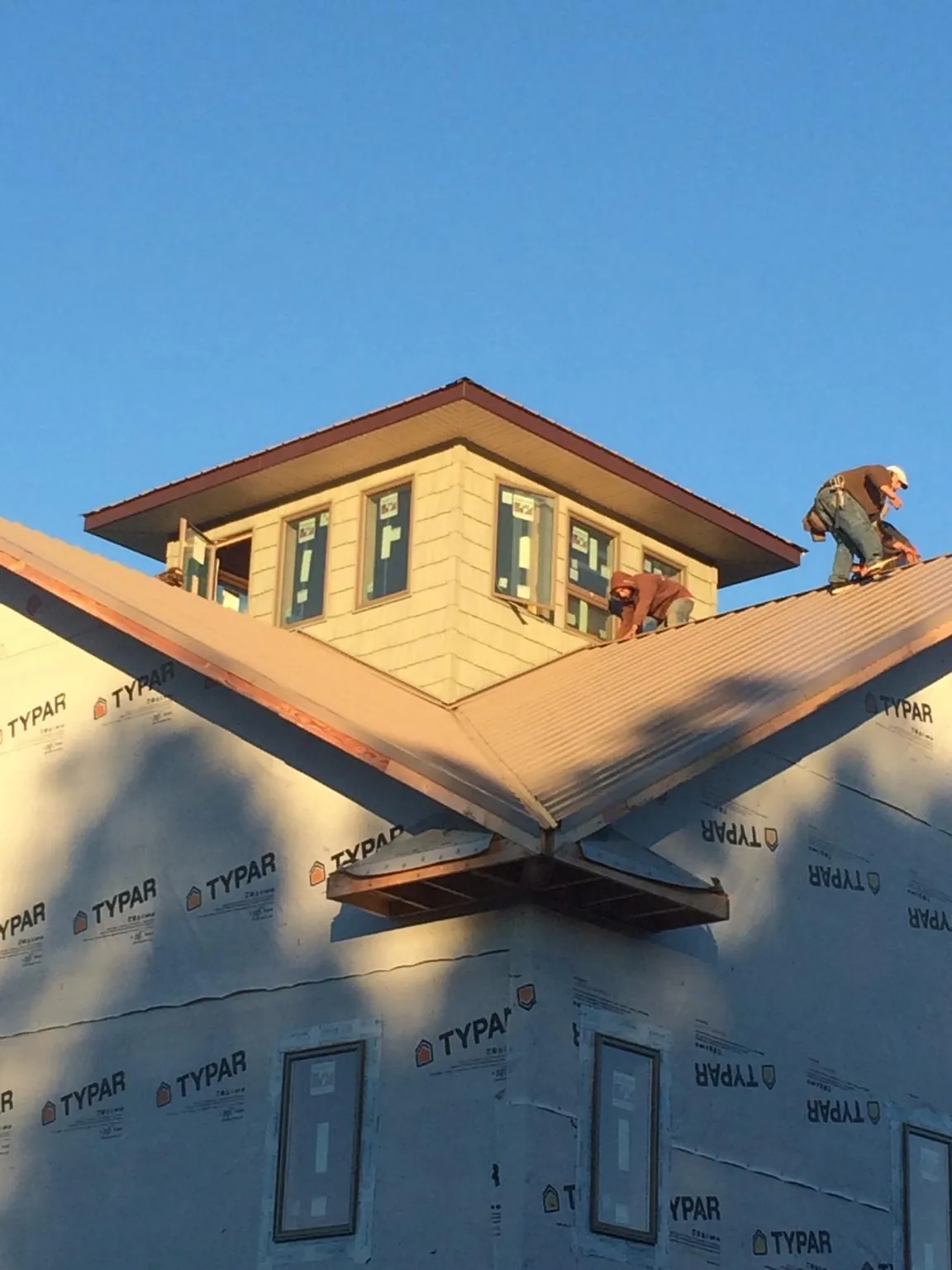 Roofers working around a rooftop cupola on a new metal roof at sunset — Roof Waterproofing in Anoka by Roofing Brothers
